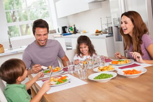 Family laughing, being thankful, sharing, around a meal in kitchen